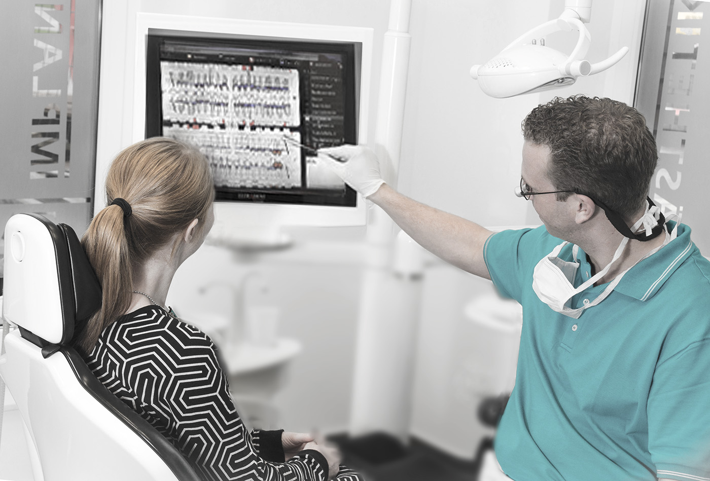 Diagnosebesprechung zwischen Zahnarzt und Patientin Zahnarzt bespricht mit einer Patientin den Zustand ihrer Zähne anhand einer Bilddarstellung am Computerbildschirm